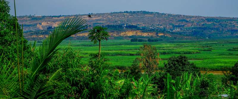 Green fields in a river valley, with hills behind.
